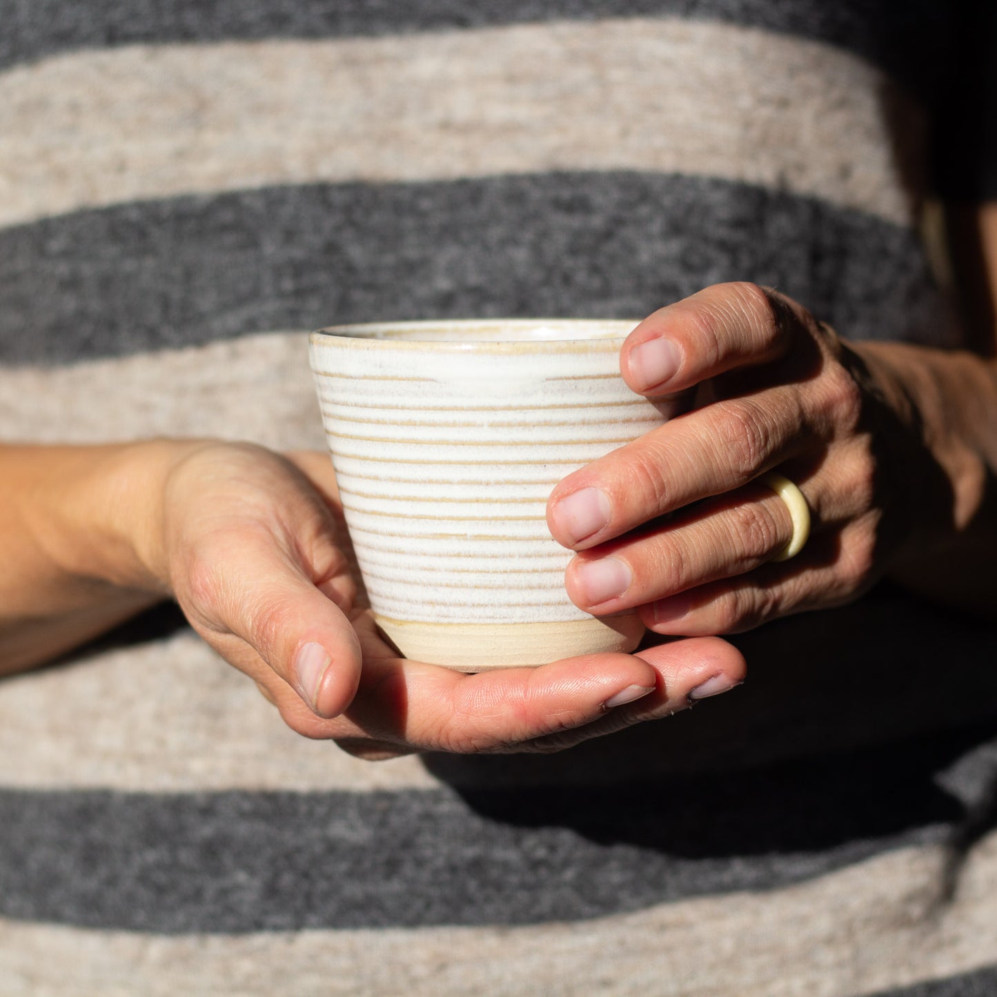 a woman wiht a ring on her finger holding a white cermic cup with two hands