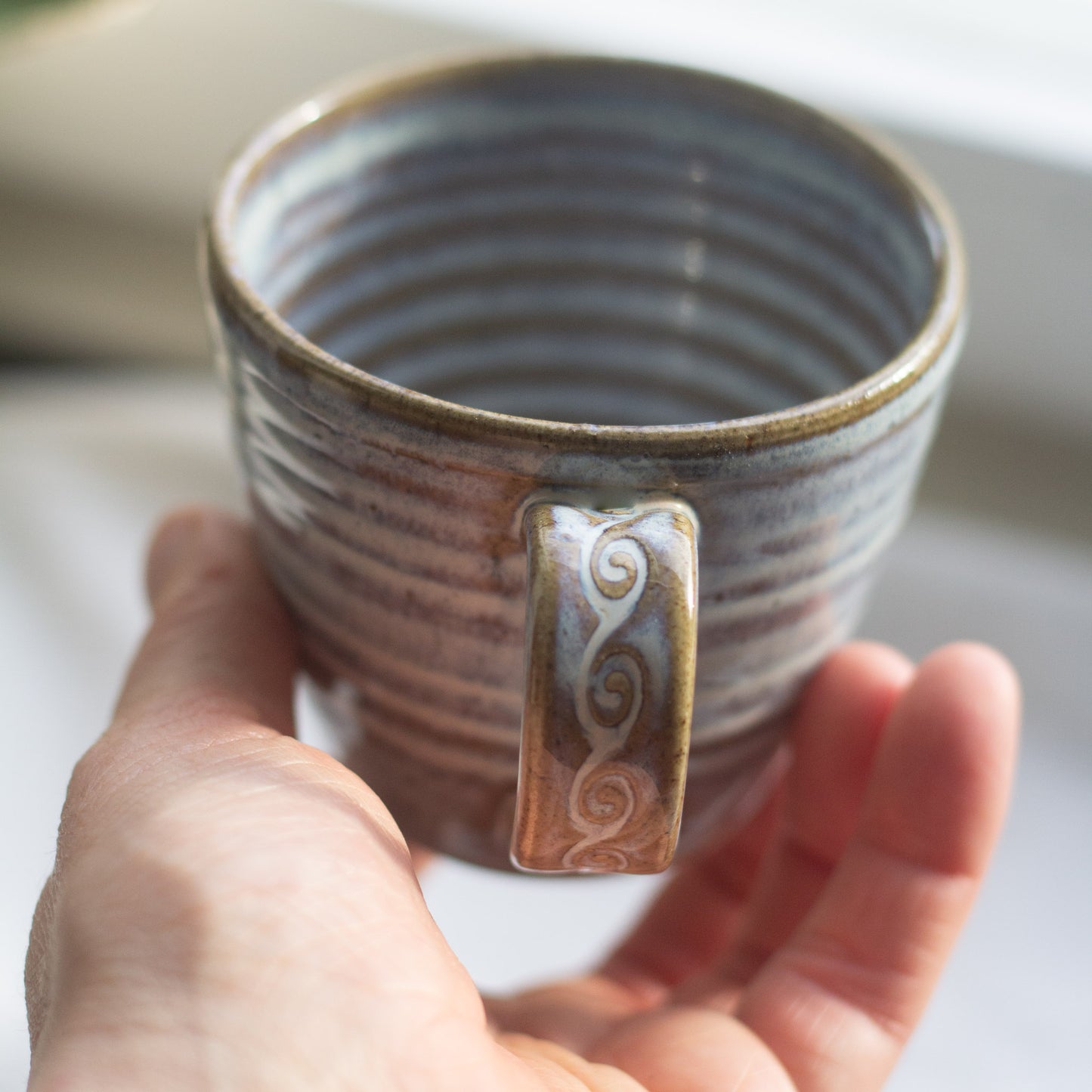 hand holding a handmade ceramic vup to showthe handle and glaze