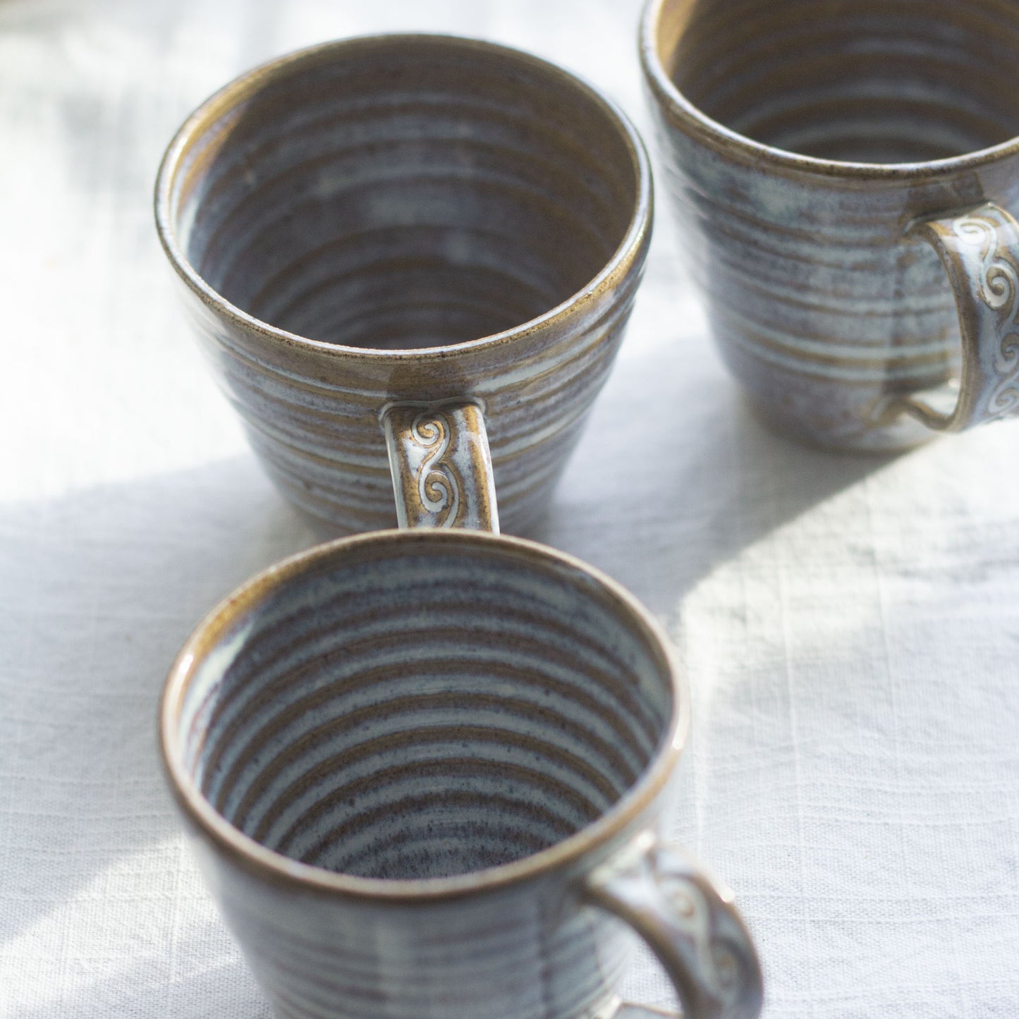 Three ceramic mugs with textured design on a white surface