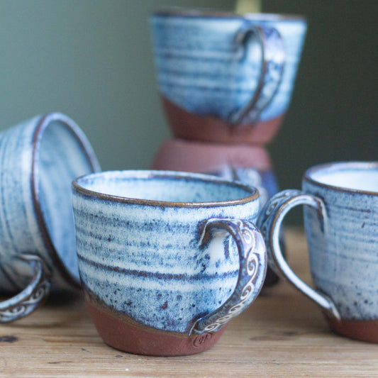 Set of blue and brown ceramic mugs on a wooden surface with a blurred background