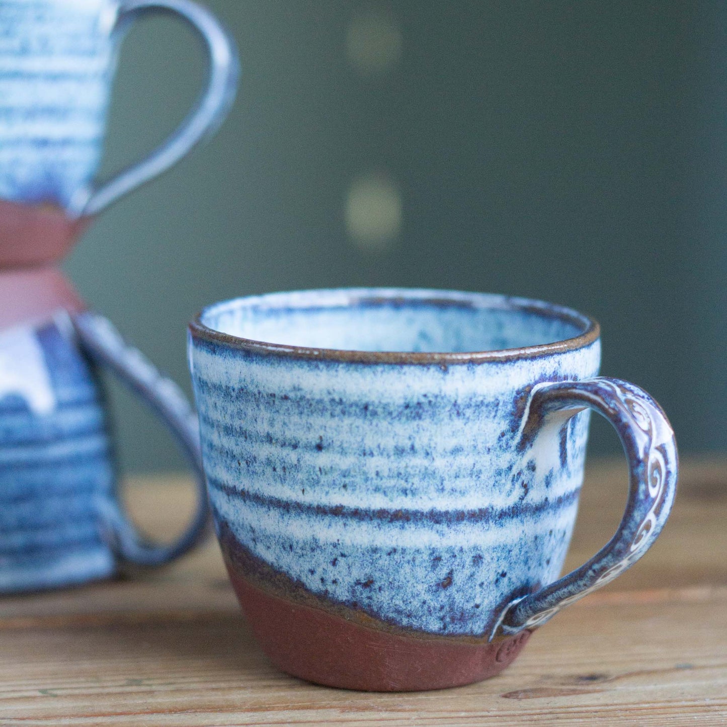 Ceramic mug with blue and brown speckled pattern on a wooden surface
