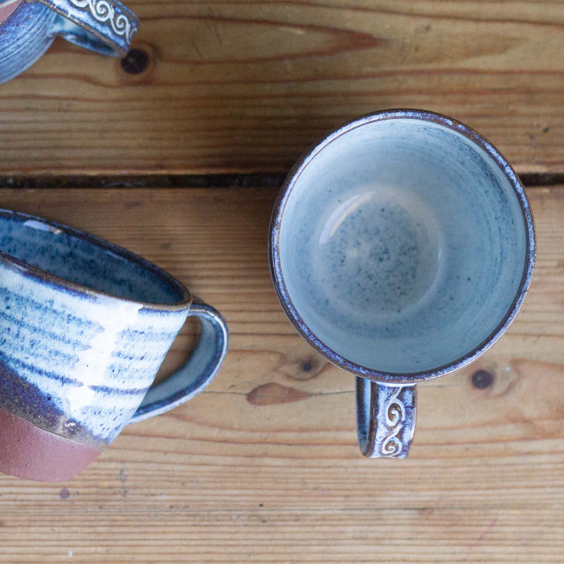 Two blue ceramic mugs on a wooden surface