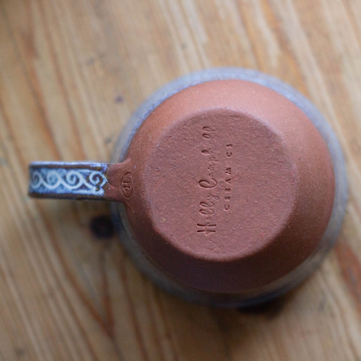 Ceramic cu
p upside down ona table  with visible branding on the botom of hte cup