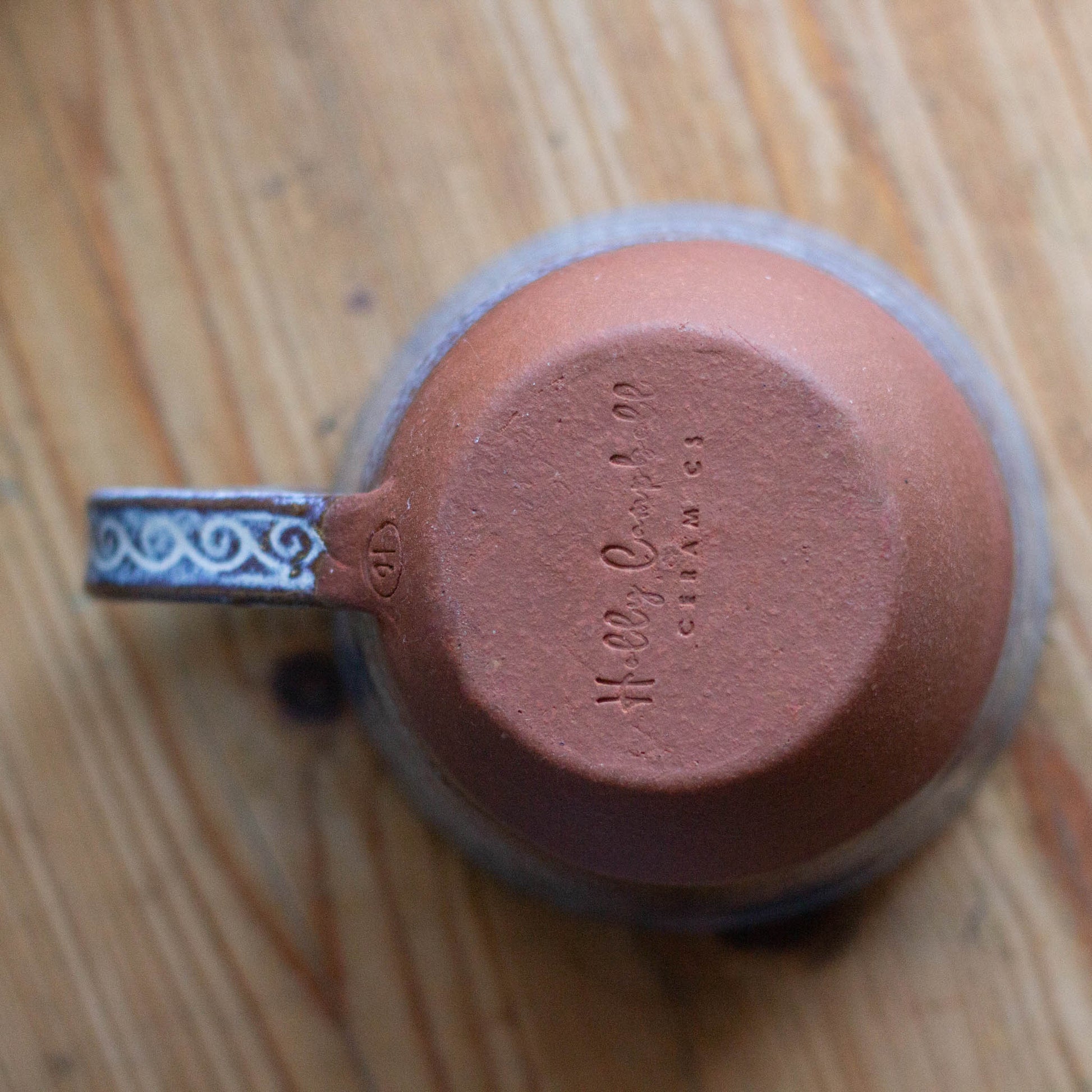 Ceramic cu
p upside down ona table  with visible branding on the botom of hte cup