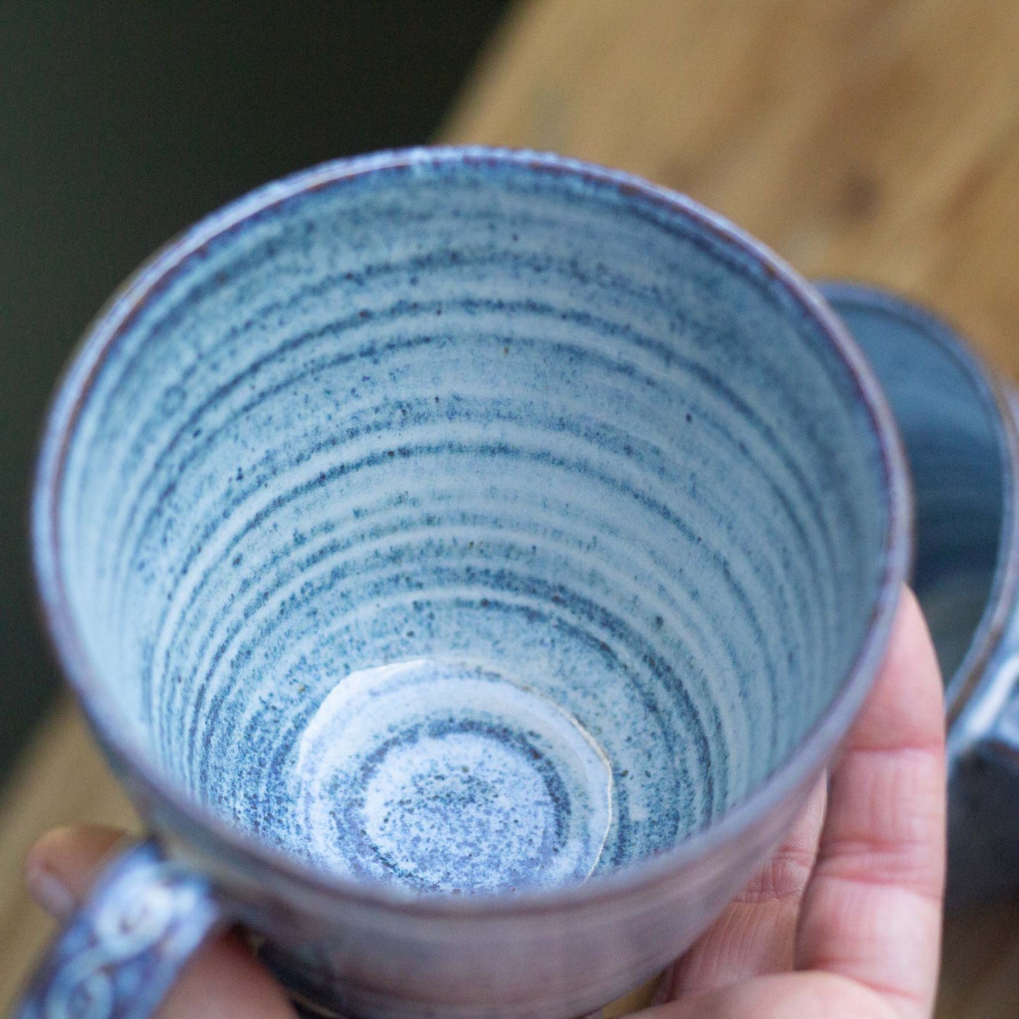 Hand holding a blue ceramic mug with a textured interior