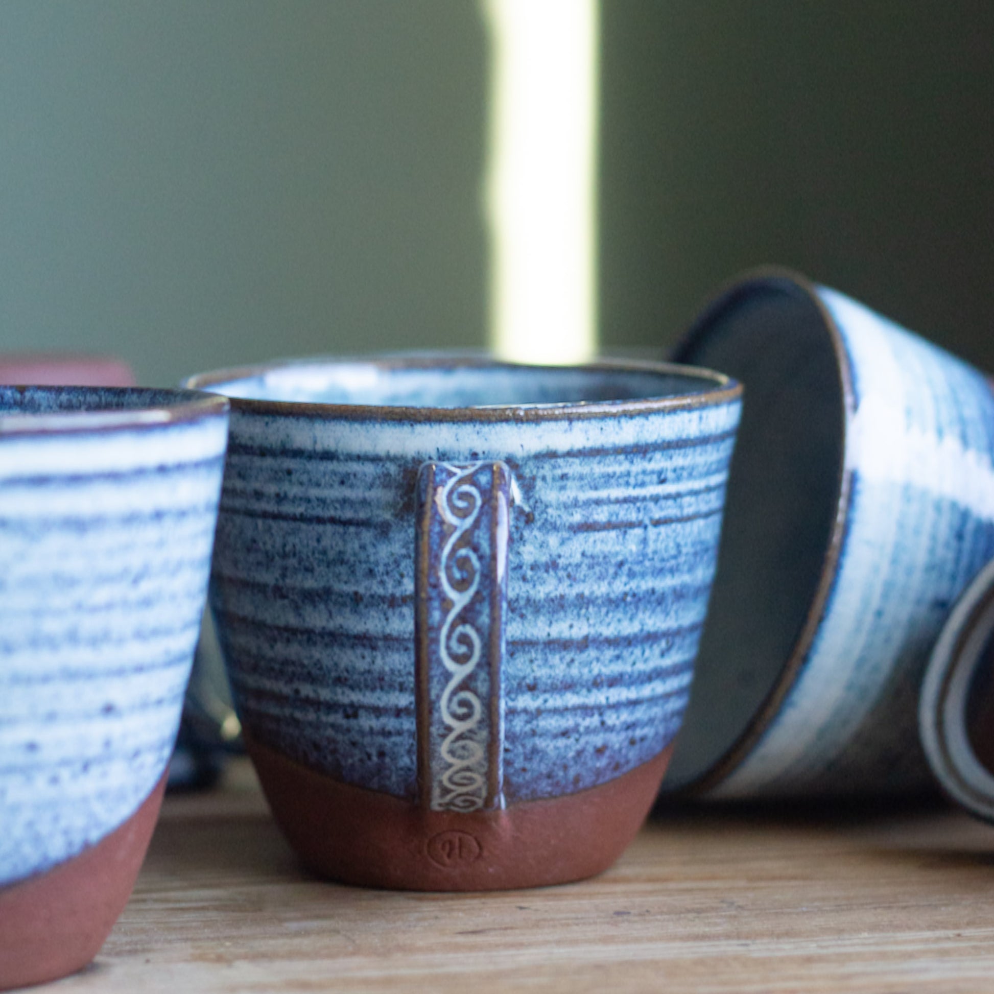 Blue ceramic cups with brown accents on a wooden surface