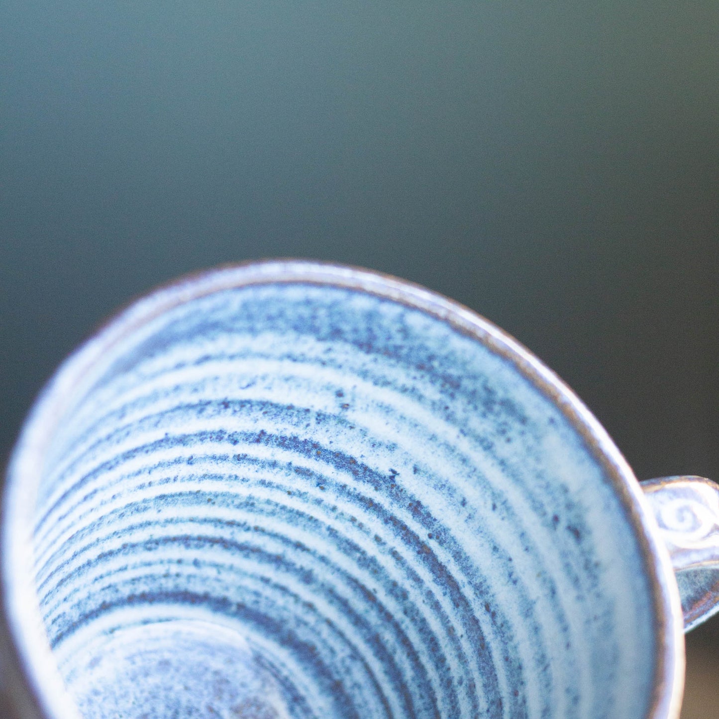 Close-up of a ceramic mug with blue speckled pattern on a blurred background