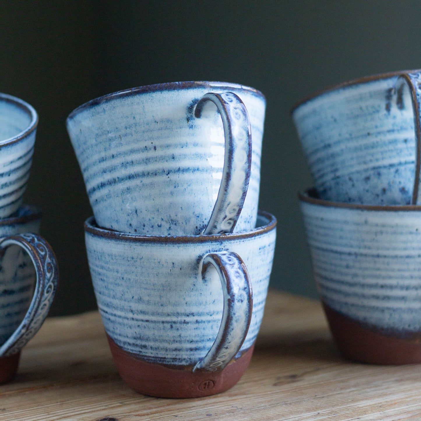 Set of blue and brown ceramic cups on a wooden surface with a dark background