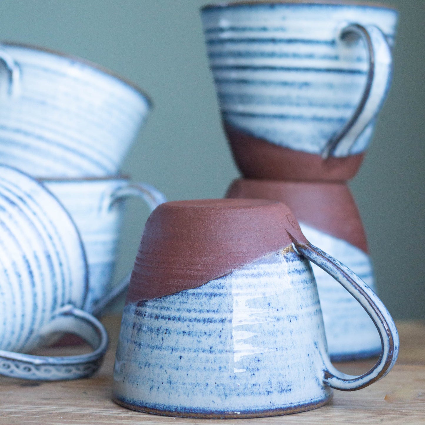 Set of ceramic cups with blue and brown patterns on a wooden surface.