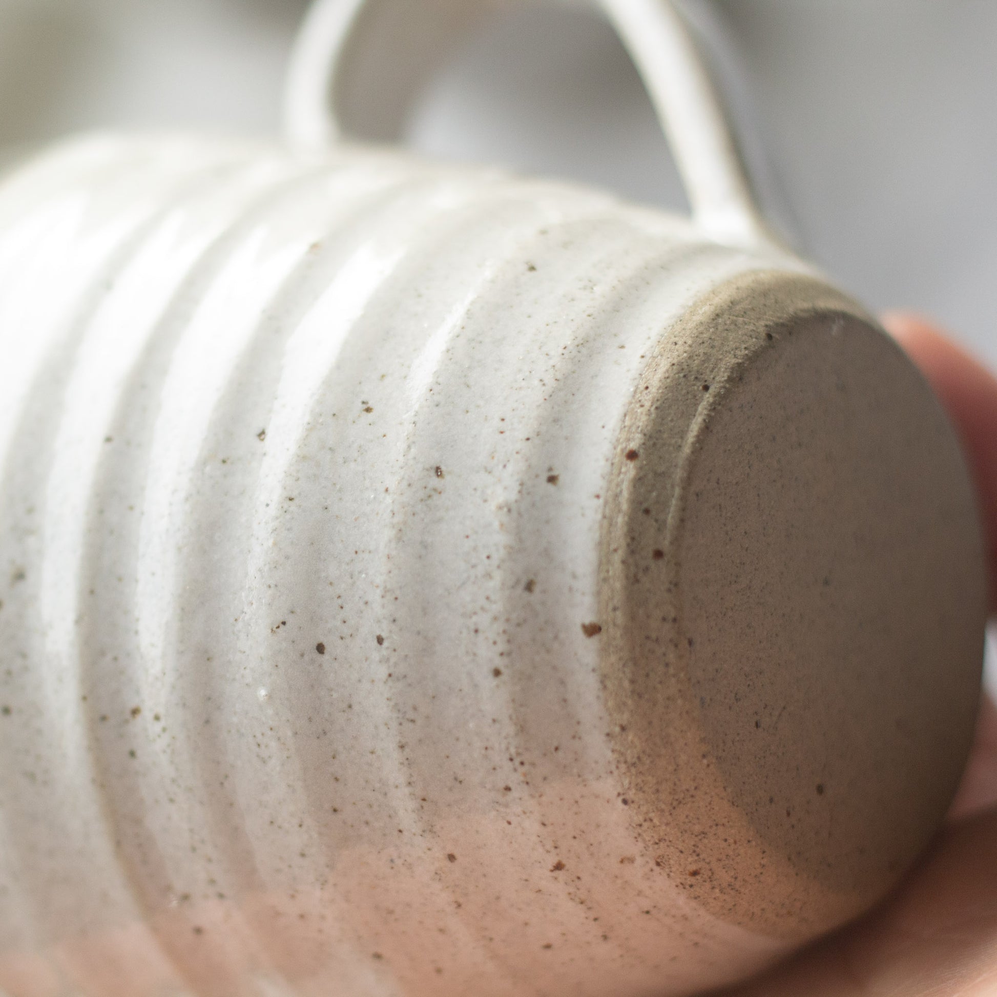 Close-up of a textured ceramic cup held by a hand