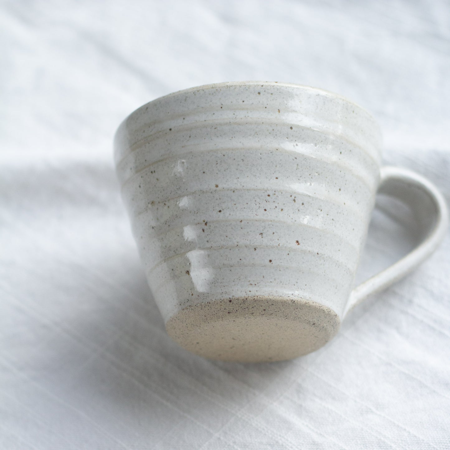 Speckled ceramic mug on a white fabric background