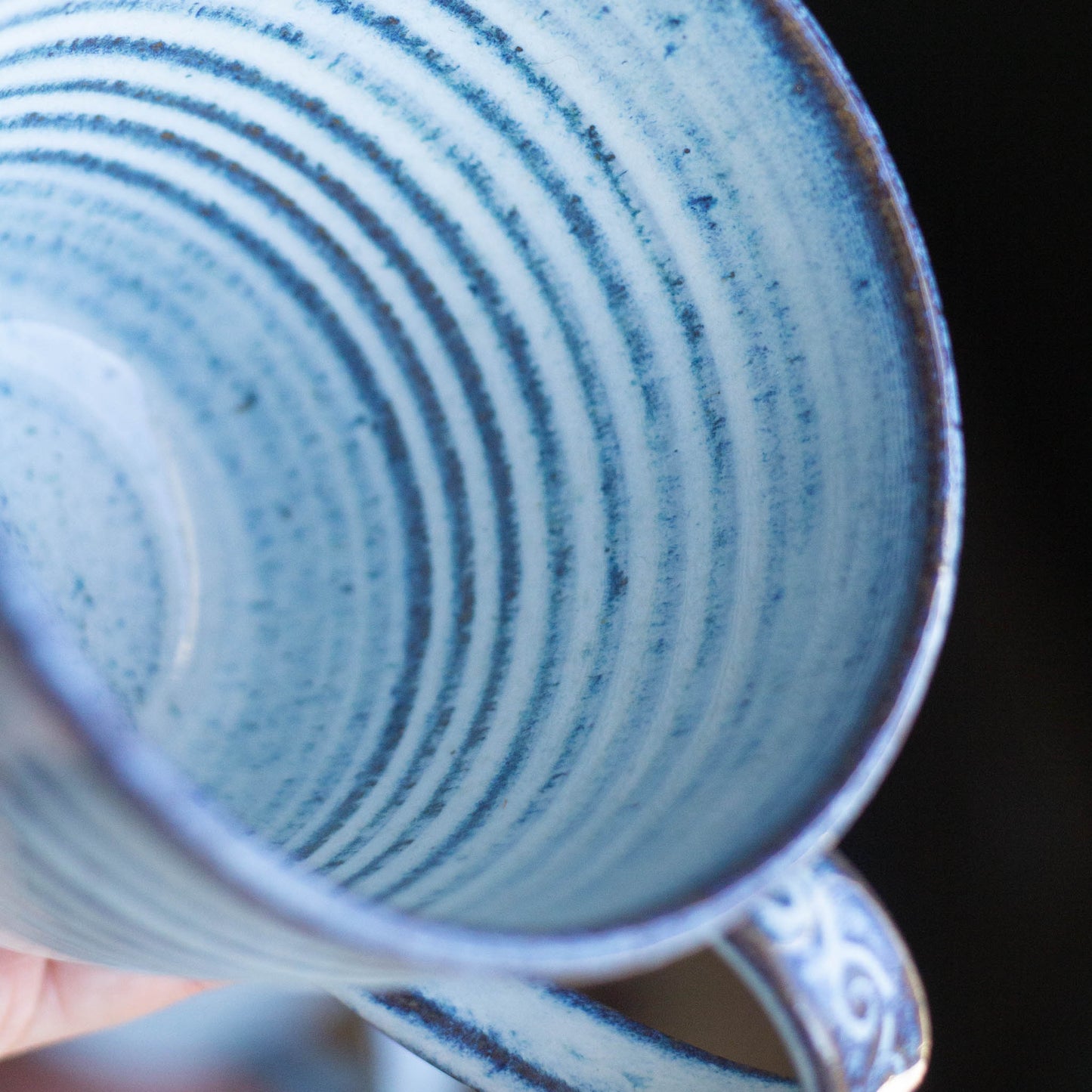 Close-up of inside of a blue ceramic mug with swirling patterns on a dark background