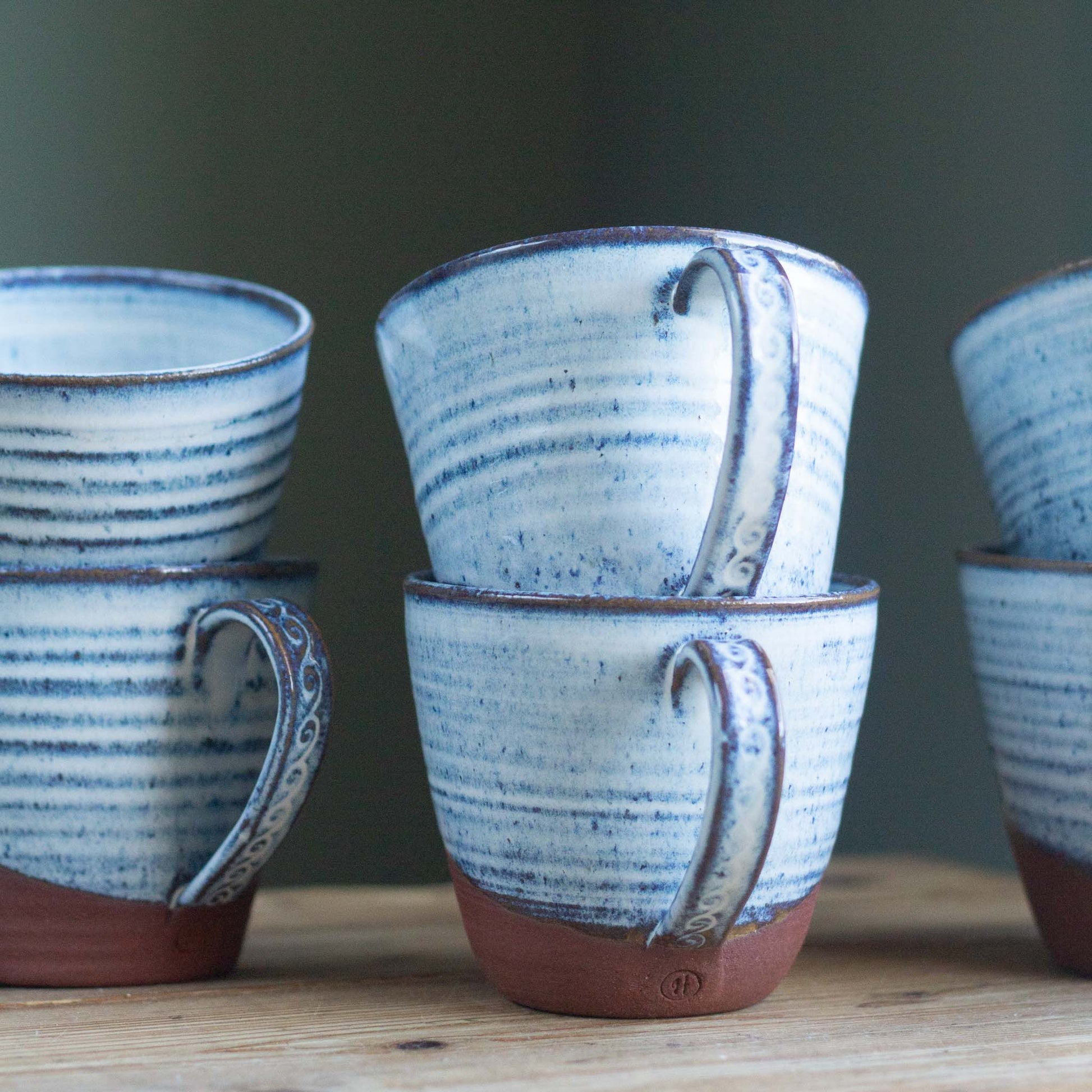 Set of blue glazed ceramic tea cups on a wooden surface with a dark background